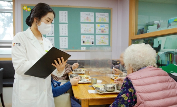 아워홈 영양사가 서울 마포구에 위치한 한서데이케어센터에서 '인지기능개선 관리 식단'을 시설 이용 어르신에게 소개하고 있다.